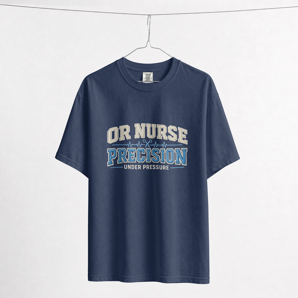 True Navy OR Nurse T-shirt on a hanger, showing the cream and blue Precision Under Pressure front print.