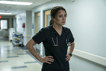 An emergency room nurse in dark scrubs taking a brief pause in a hospital corridor