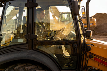 A heavy equipment operator seated in the cab of a large wheel loader on a construction site