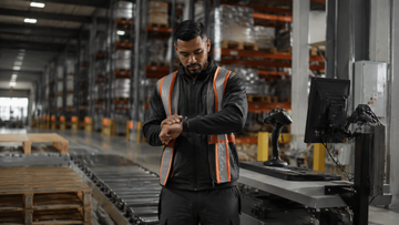Early shift warehouse worker checking the time before starting work