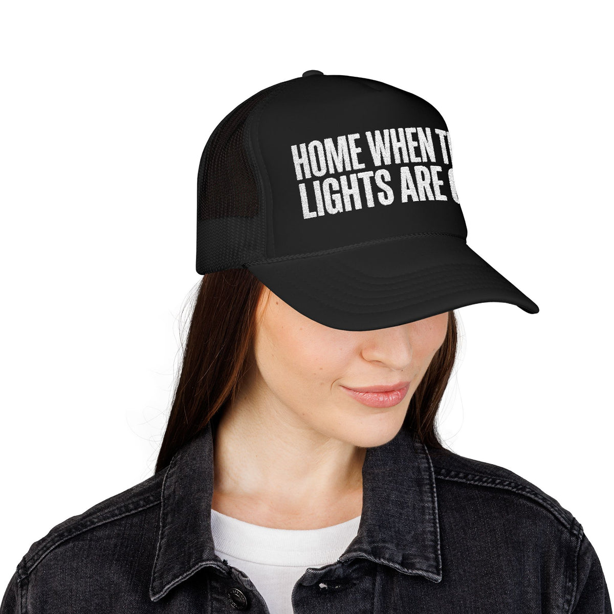 Woman wearing the black Home When The Lights Are On trucker hat with a denim jacket.