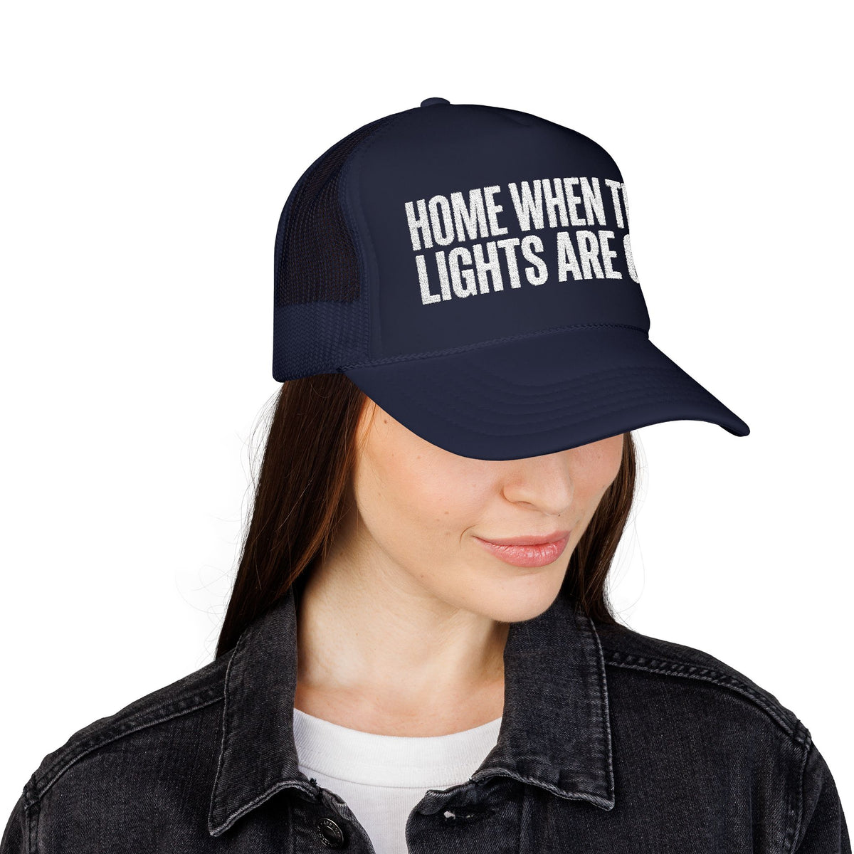 Woman wearing the dark navy Home When The Lights Are On trucker hat with a denim jacket.