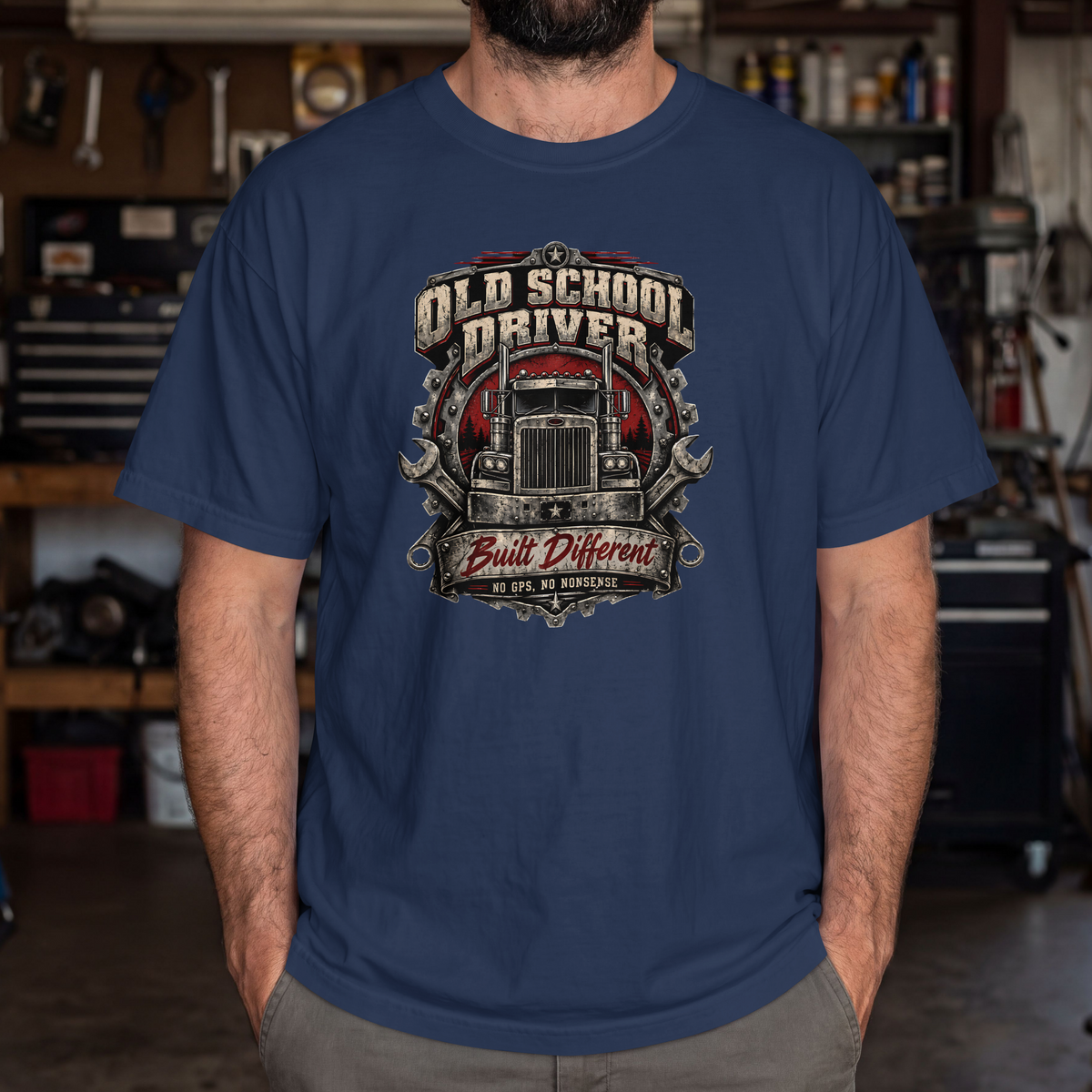 True Navy Old School Driver Built Different T-shirt worn by a model in a workshop, showing the front semi-truck graphic.