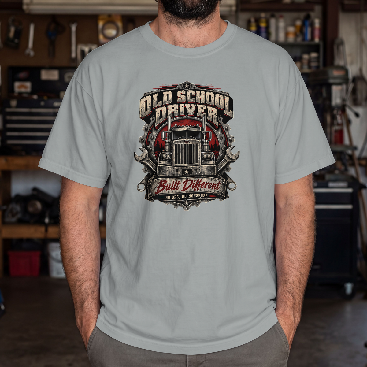 Granite Old School Driver Built Different T-shirt worn by a model in a workshop, showing the front semi-truck graphic.