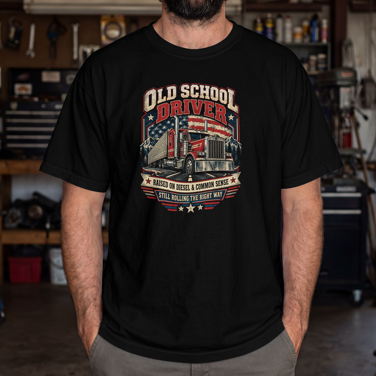 Black Old School Driver T-shirt worn by a model in a workshop, showing the semi-truck and American flag front design.