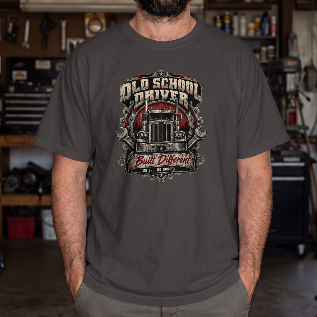 Pepper Old School Driver Built Different T-shirt worn by a model in a workshop, showing the front semi-truck graphic.