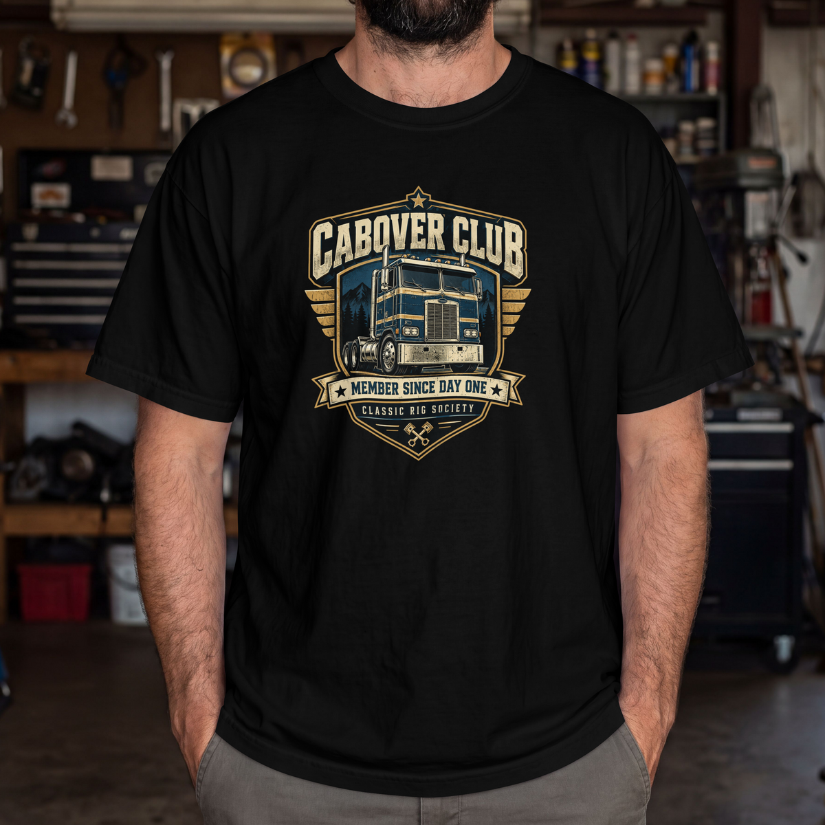 Black Cabover Club T-shirt with blue and gold vintage cabover truck graphic and Member Since Day One lettering, male model in workshop.