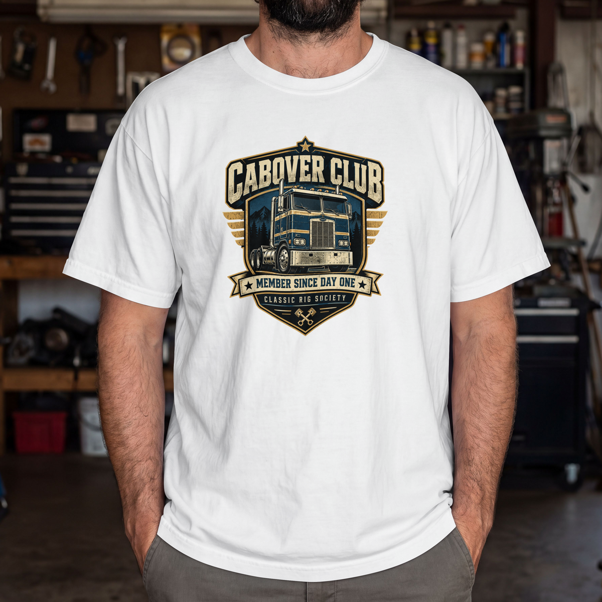 White Cabover Club T-shirt with blue and gold vintage cabover truck graphic and Member Since Day One lettering, male model in workshop.