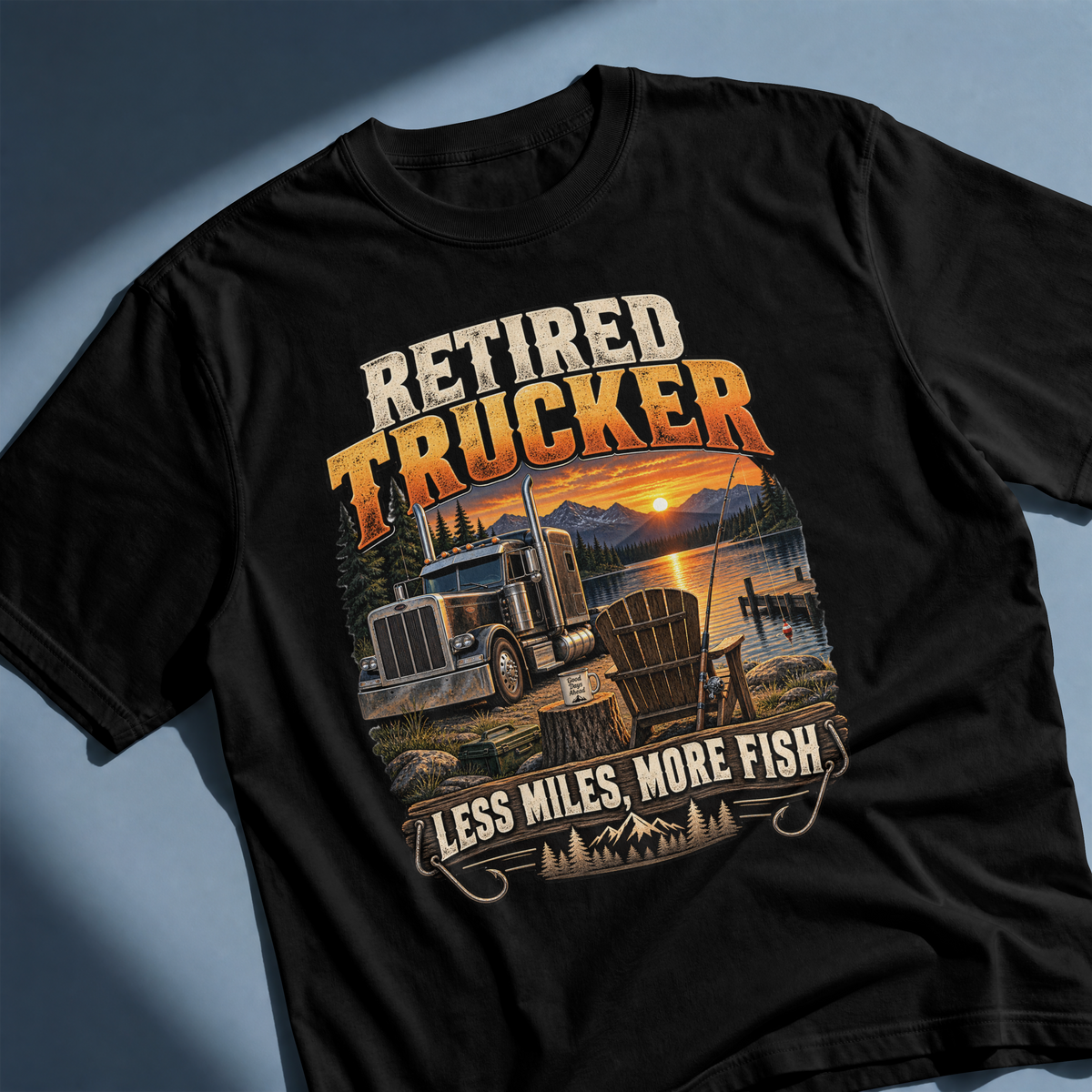 Black Retired Trucker Less Miles More Fish T-shirt laid flat, showing the semi-truck, lakeside chair and fishing artwork.