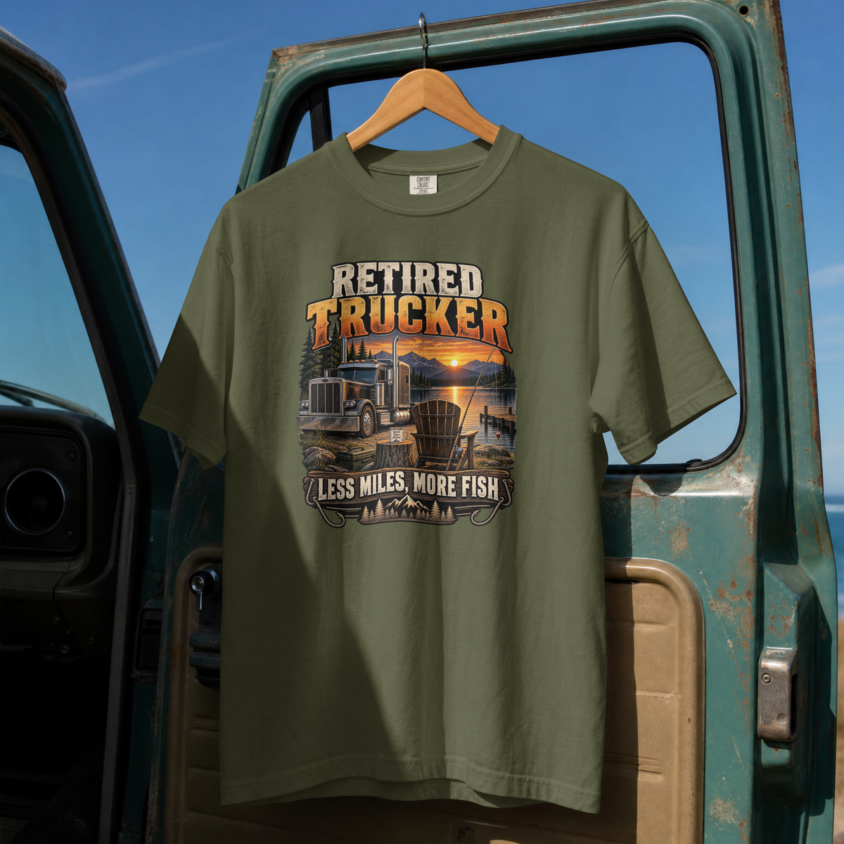 Hemp Retired Trucker Less Miles More Fish T-shirt, full front hanging view with truck and lakeside fishing graphic.