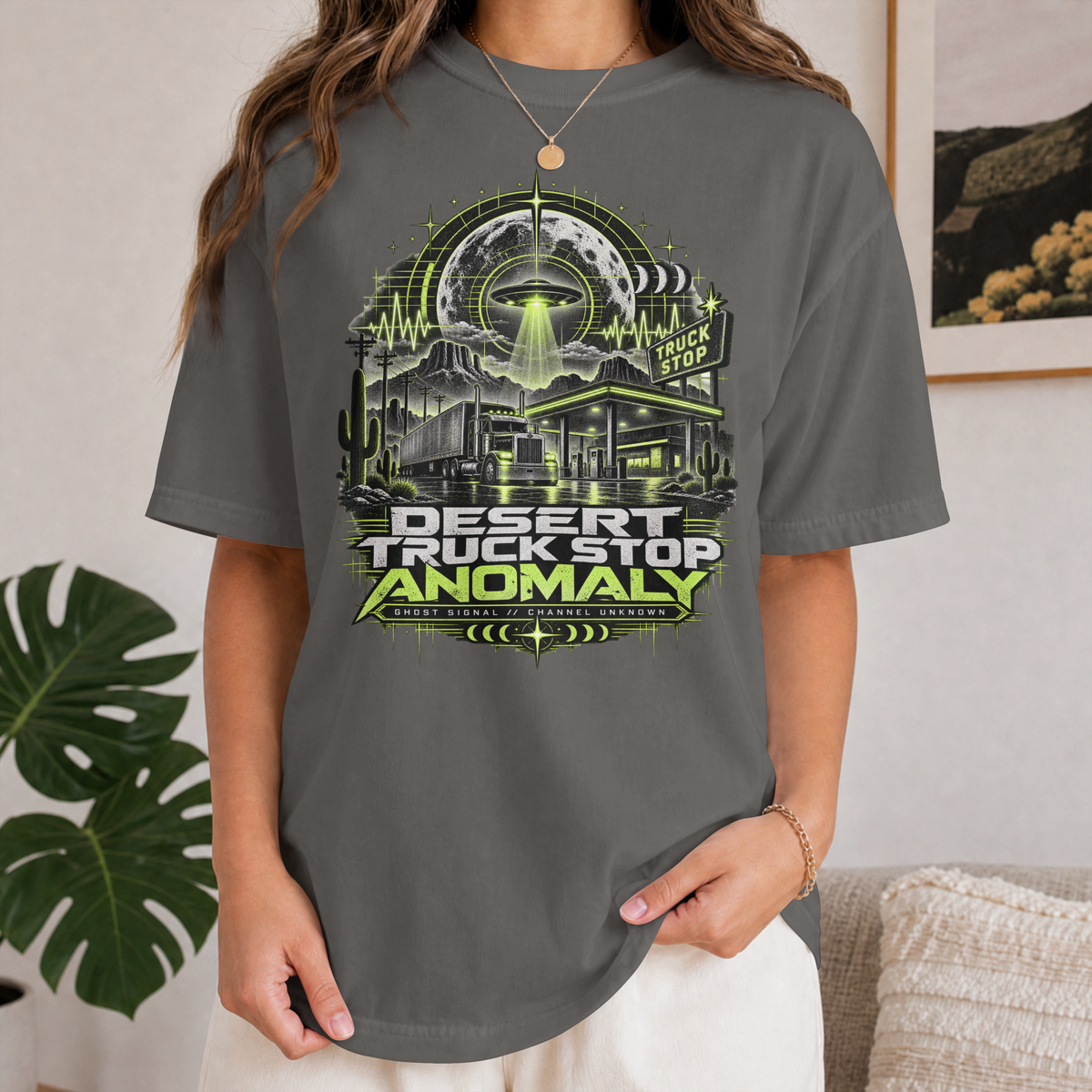 Pepper Desert Truck Stop Anomaly T-shirt worn by a female model, showing the green UFO, moon and desert truck stop front graphic.