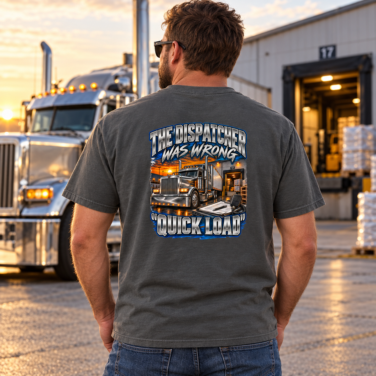 Back view of model wearing Pepper gray Dispatcher Was Wrong T-shirt beside a parked semi truck at a loading dock.