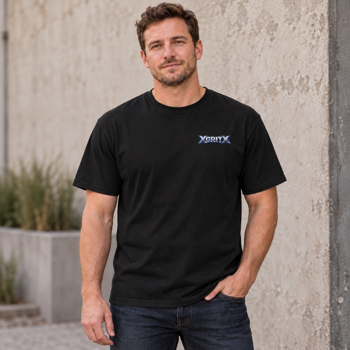 AI lifestyle mockup showing the front of a Black XGRITX T-shirt worn by a male model, with a small silver-and-blue left-chest logo.