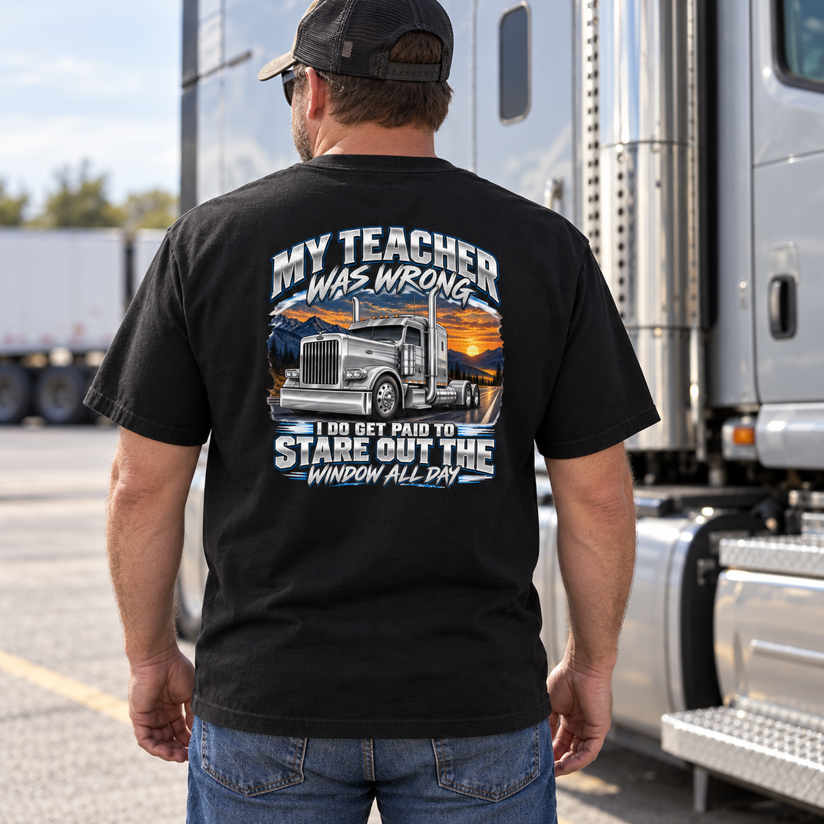 Rear view of a model wearing Black My Teacher Was Wrong T-shirt beside a parked silver semi truck.