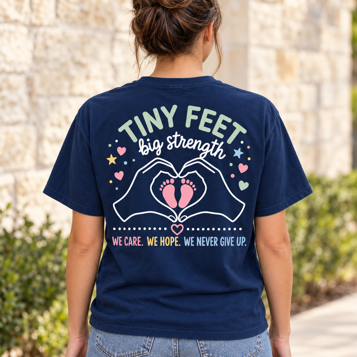 Woman showing the complete Tiny Feet Big Strength back design on the True Navy XGRITX NICU T-shirt